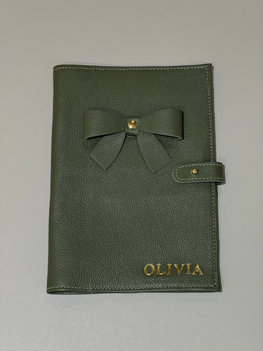 Detalhe do grão do couro oliva, laço aplicado e hot stamping dourado